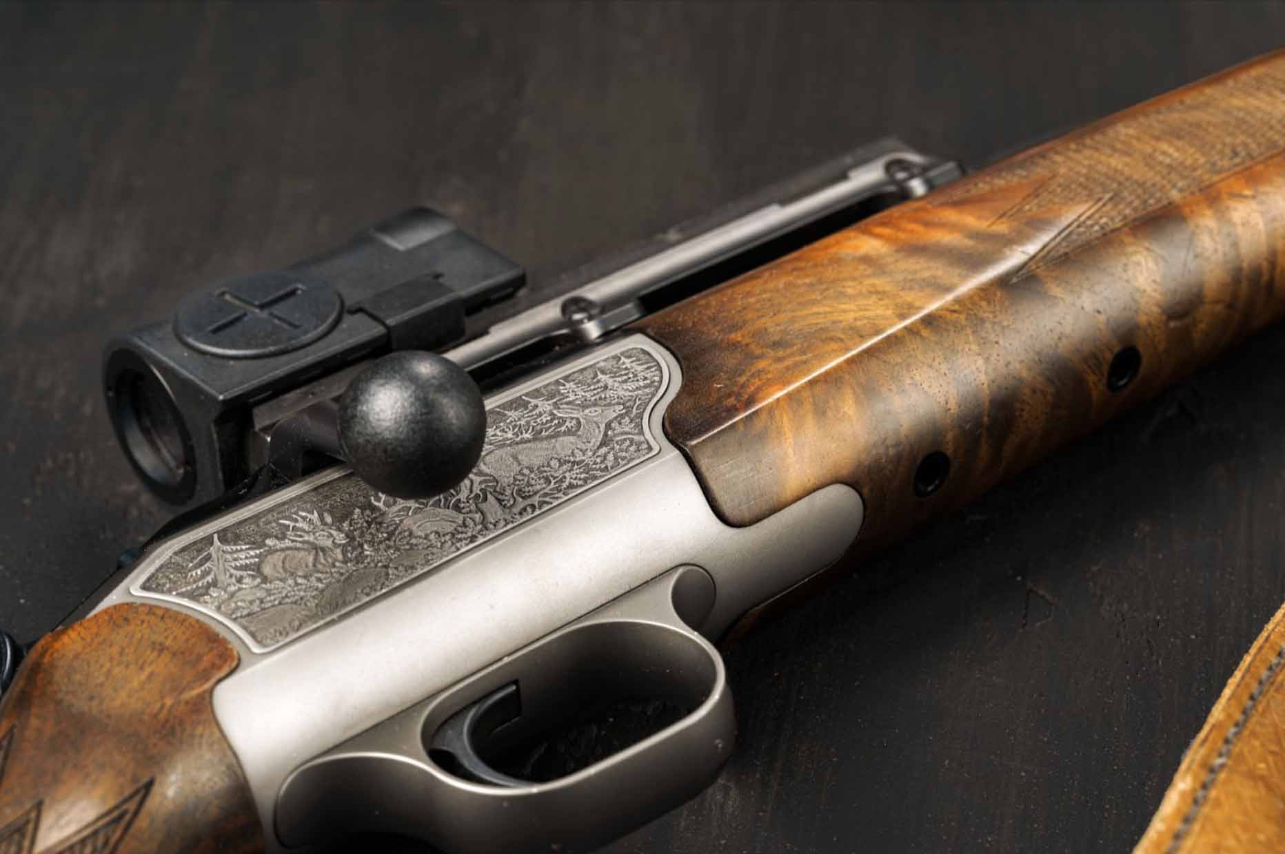 A close-up shot of a hunting rifle with a polished wooden stock and metal trigger, set against a black background for contrast.