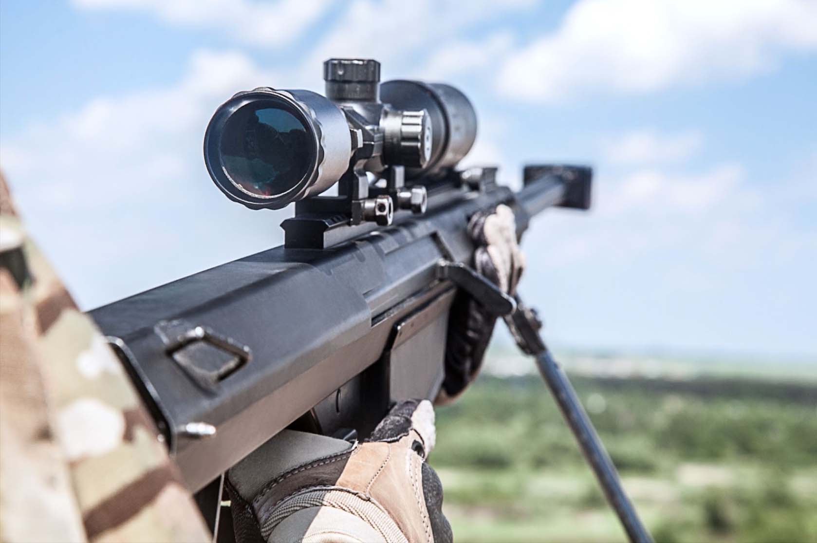 A detailed close-up of a military sniper rifle, showcasing the attached scope prominently for precision targeting.