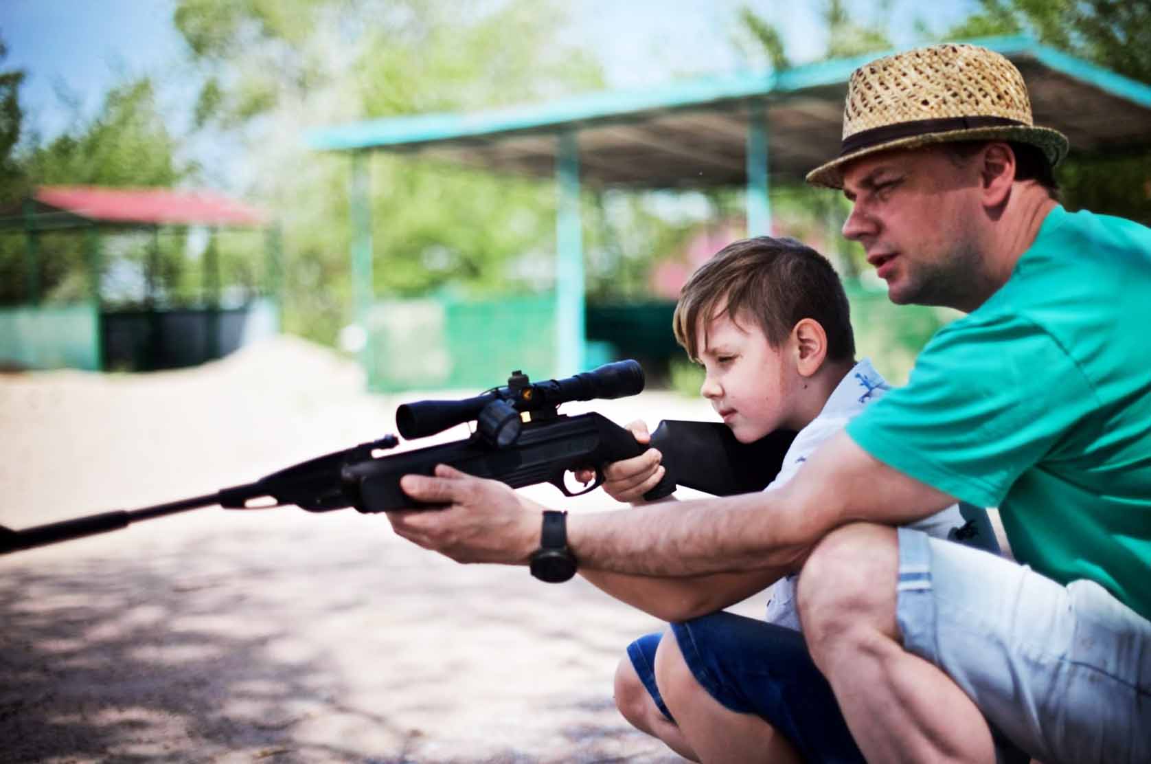 A father teaches his son how to shoot a rifle.