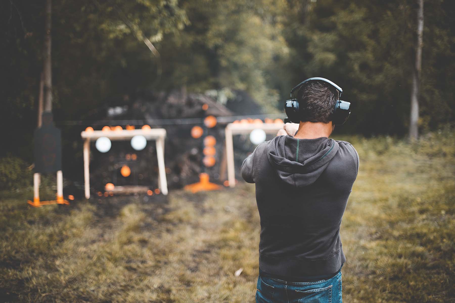 A male practices gun shooting outdoors.