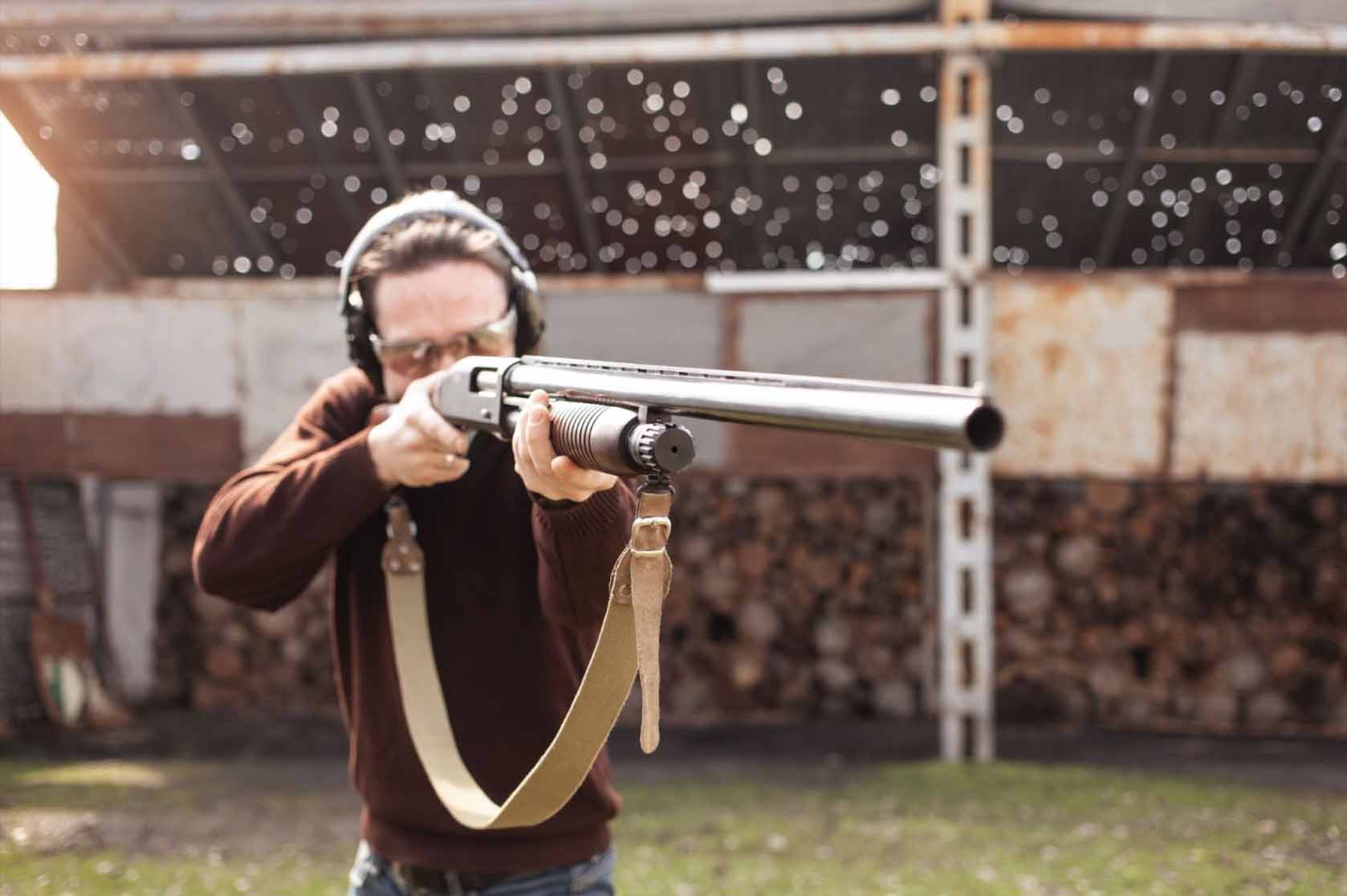 A male shooter wearing a brown long-sleeved shirt in action during an outdoor long-range shooting competition.