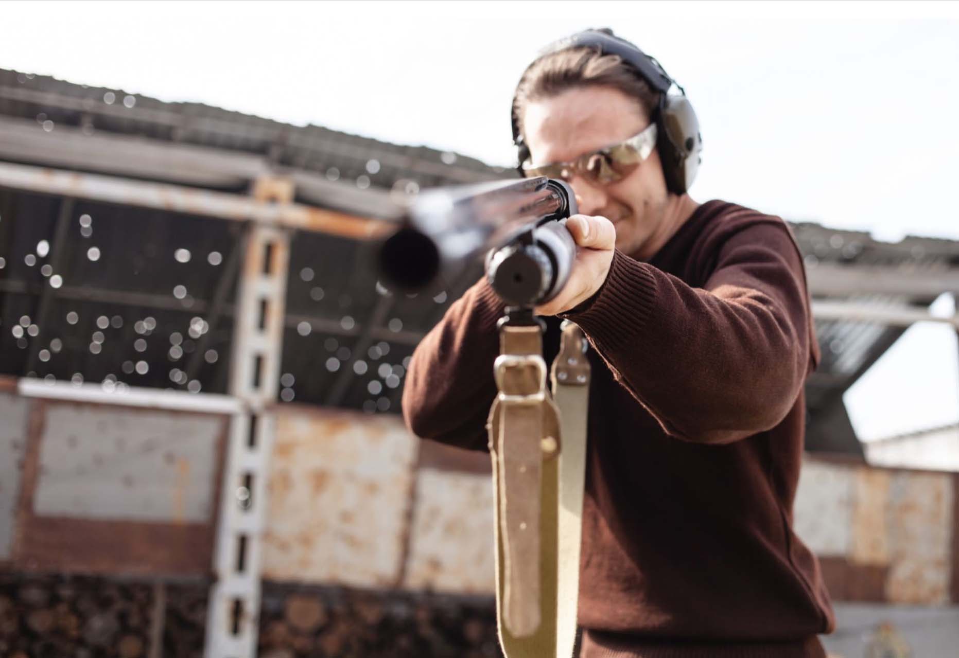 A man aims a shotgun at targets in a shooting range.