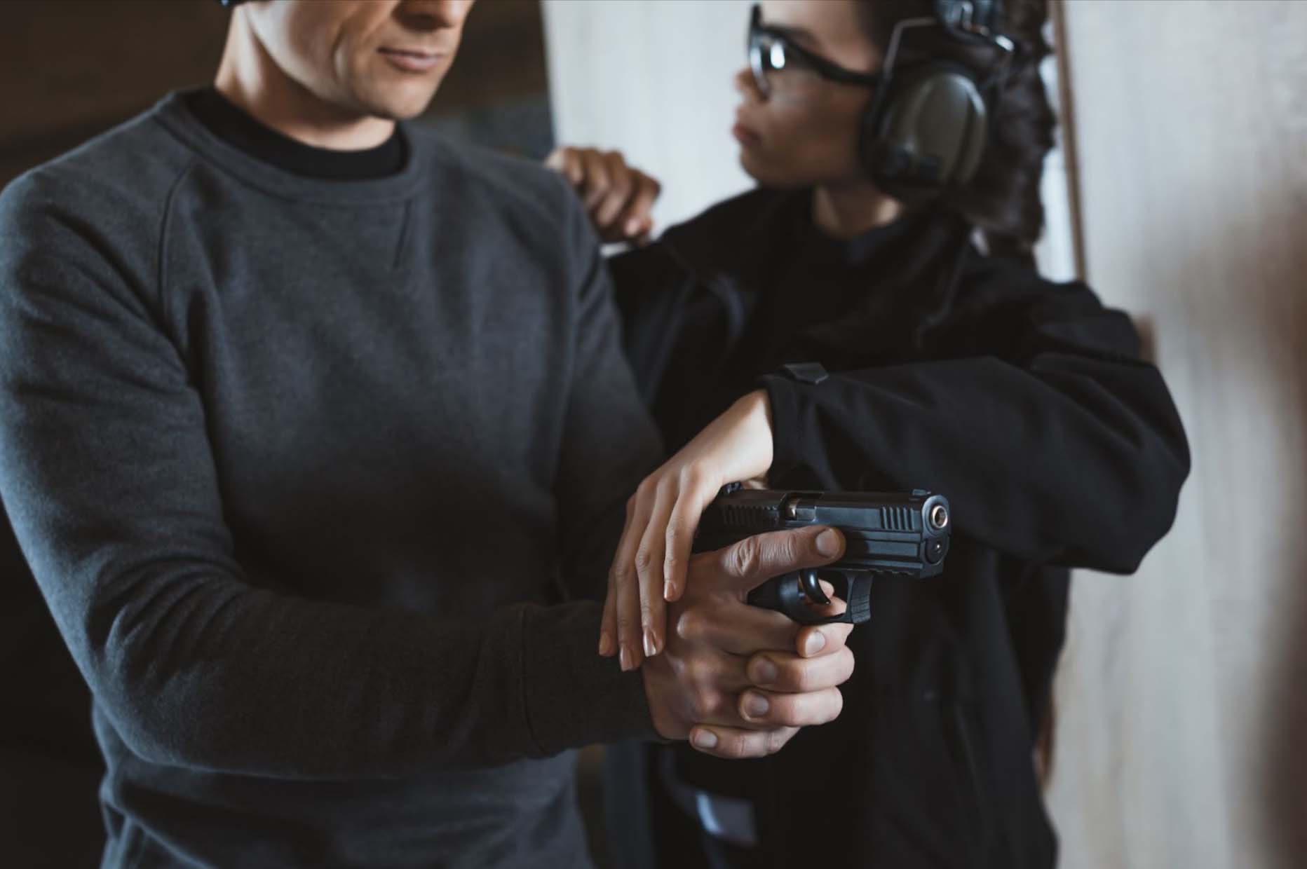Female instructor helping a man who is holding a gun.
