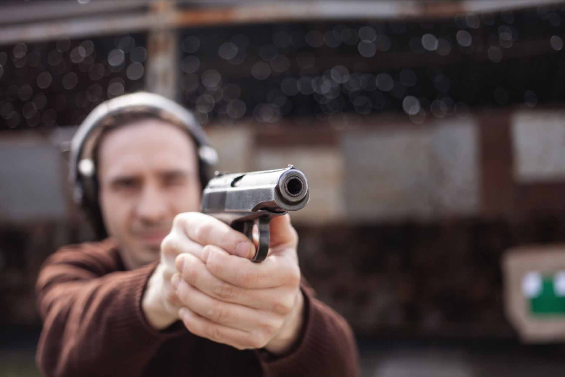 Man holding a gun with headphones on.