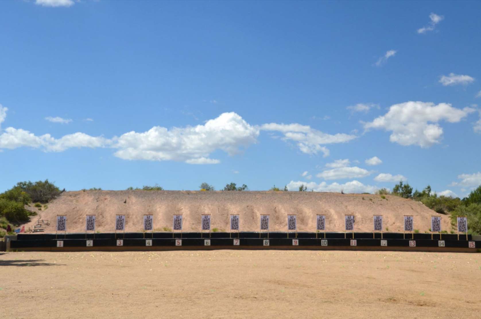Paper targets set up for firearms training at an outdoor gun range, with a gravel berm as a backdrop.