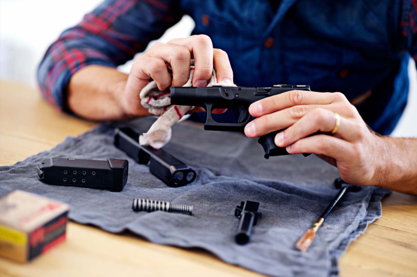 Regular maintenance is essential for every gun owner, as depicted by the cropped view of a man cleaning his gun.