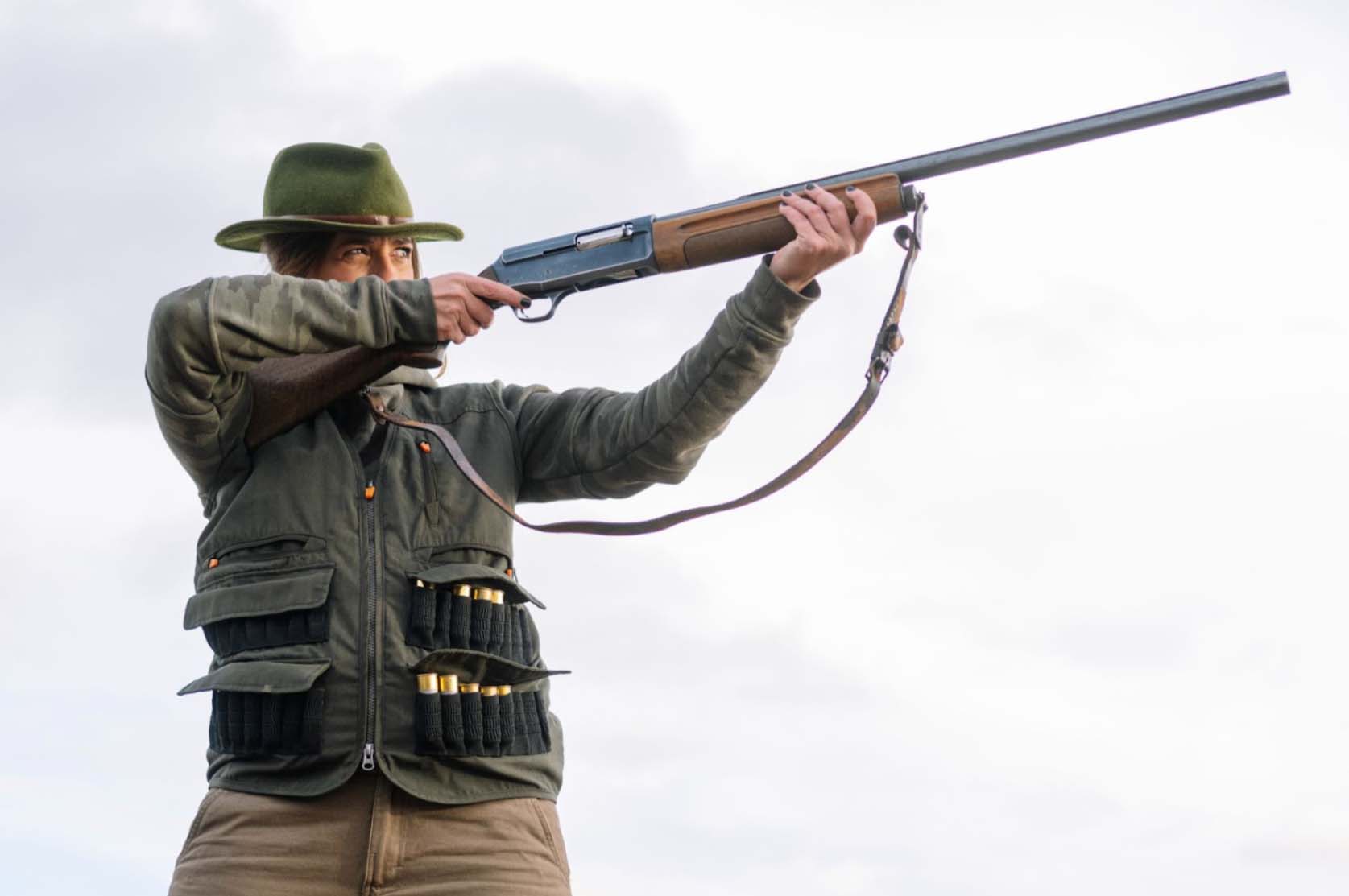 Woman holding and aiming a shotgun in the air.